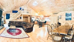 A spacious living area with a stone fireplace, leather sectional sofa, and a dining table with chairs.
