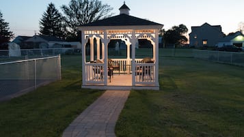 A gazebo with a brick pathway leading to it, surrounded by a chain-link fence.