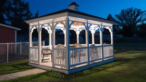 Un belvédère doté d’un patio couvert, comprenant un banc et des chaises en osier.