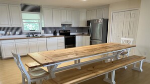 A kitchen with white cabinets, a wooden dining table with benches, and a stainless steel refrigerator. - 4 Bedrooms, 4  Baths; Just Steps to the Ocean!  Fronts on Point St. (Edisto Beach)