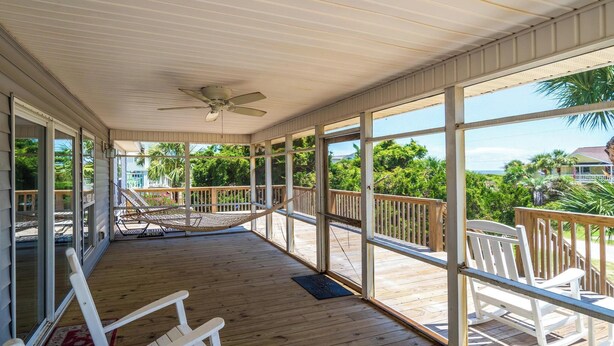 A covered outdoor deck with wooden flooring, white rocking chairs, and a hammock. - 4 Bedrooms, 4  Baths; Just Steps to the Ocean!  Fronts on Point St. (Edisto Beach)