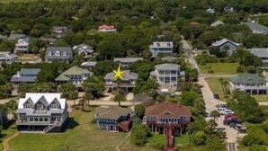 An aerial view of a coastal area with multiple houses, a prominent building with a star symbol, and several beach tents. - 4 Bedrooms, 4  Baths; Just Steps to the Ocean!  Fronts on Point St. (Edisto Beach)