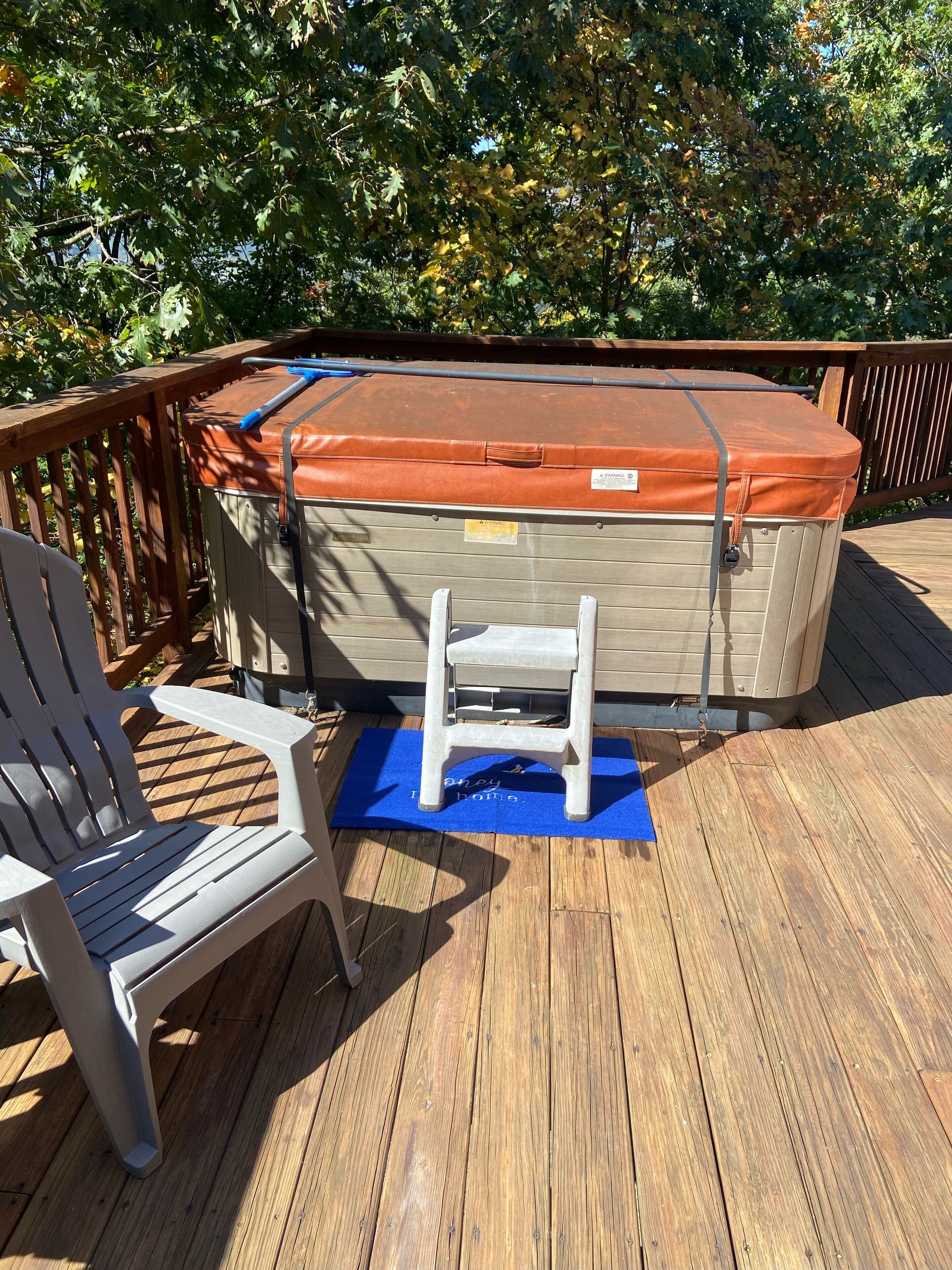 Een hottub met een houten terras en een witte stoel.