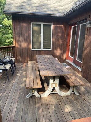 Una terraza de madera con una mesa de picnic y sillas.