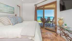 A bedroom with a bed, a ceiling fan, a TV, a painting, and a view of the ocean through a sliding door. - Villa #18:  LUXURY 5 Bed/5 bath Oceanfront home for 14 guests.  Renovated 3/26. (Puerto Peñasco)
