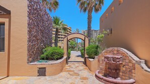 A stone pathway leading to a building entrance, flanked by a stone wall and a decorative fountain. - Villa #18:  LUXURY 5 Bed/5 bath Oceanfront home for 14 guests.  Renovated 3/26. (Puerto Peñasco)