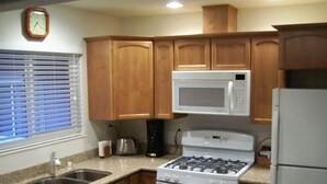 A kitchen with wooden cabinets, a gas stove, a microwave, and a refrigerator. - Best North Napa Location, Close to Wineries & Restaurants (Napa)