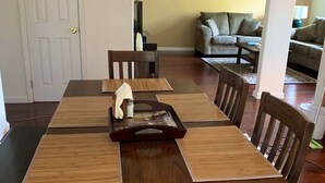 A dining area with a wooden table and chairs, a tray with a bottle, and a sofa in the background. - Best North Napa Location, Close to Wineries & Restaurants (Napa)