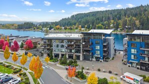 A modern multi-story building with balconies, a U-Haul truck, and a waterfront view. - NOW AVAILABLE FOR LABOR DAY! Coeur d’Alene Luxury Waterfront Condo (Coeur d'Alene)