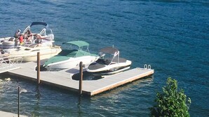 A marina with boats docked, a dock with a covered area, and a forested hill in the background. - NOW AVAILABLE FOR LABOR DAY! Coeur d’Alene Luxury Waterfront Condo (Coeur d'Alene)