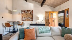 Een gezellige woonkamer met een bank, stoelen, een tafel en kunst aan de muur.