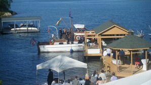 A boat docked at a pier with a covered seating area and a small pavilion. - Luxury on Lake Keowee - FALL & Summer 2027 NOW OPEN (Seneca)