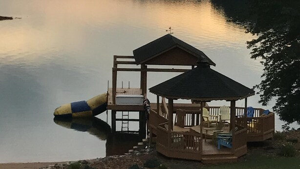 A wooden dock with a gazebo, a small boat, and a grassy area by a calm lake. - Luxury on Lake Keowee - FALL & Summer 2027 NOW OPEN (Seneca)