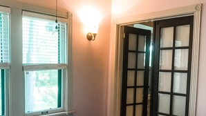 Quarto com cama, ventilador de teto e janela com persianas.