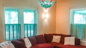 Sala de estar com um sofá seccional vermelho, uma poltrona estampada e um lustre de vidro colorido.