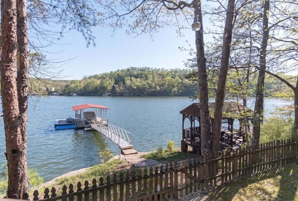 Une vue sur le lac, avec un quai, un kiosque et une clôture en bois.