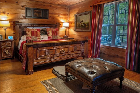 A wooden cabin bedroom with a large bed, a leather bench, and a window with curtains. - Perfect cozy cabin RL vibe for the fall and holiday season❤️🔥🍁🎄 (Crane Hill)