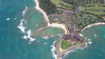 An aerial view of a coastal resort with a central building surrounded by a beach and ocean.