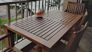 A wooden table and chairs on a balcony overlooking the ocean with palm trees. - Oceanfront Penthouse Condominium Spectacular Beachfront View (Kihei)