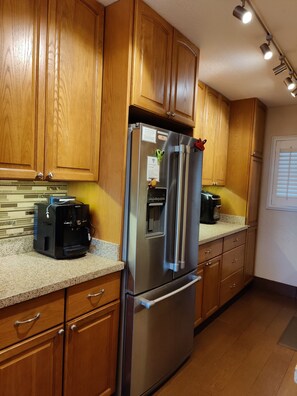 A kitchen with wooden cabinets, a stainless steel refrigerator, a coffee maker, and a built-in oven.