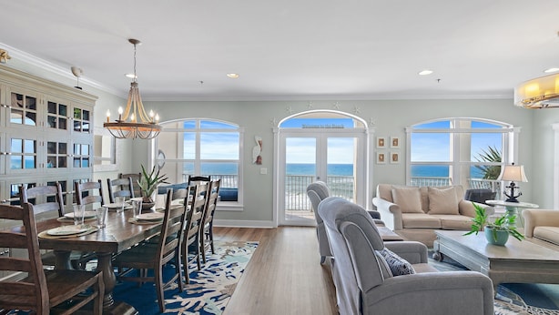 A spacious living room with a large window overlooking the ocean, a dining area with a chandelier, and a cozy seating area with a view. - GULF-FRONT, Cancellation, Balcony, Grill, Pool, Updated! (Santa Rosa Beach)
