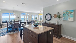 A spacious kitchen with a large island, dark wood cabinetry, and a view to the outside. - GULF-FRONT, Cancellation, Balcony, Grill, Pool, Updated! (Santa Rosa Beach)