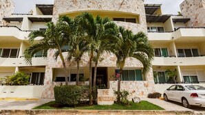 A multi-story building with a stone facade, palm trees in front, and a sign reading "THE MERIDIAN".