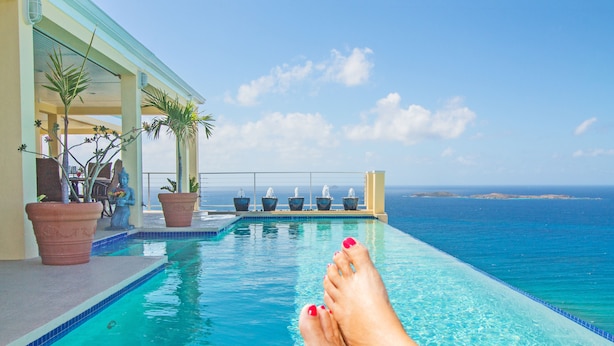 Une piscine avec vue sur l’océan, des plantes en pot et un fauteuil.