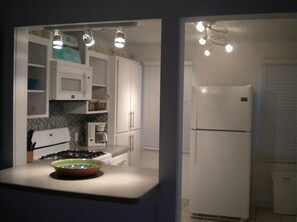 Fully equipped kitchen with appliances, central island, and tiled backsplash.