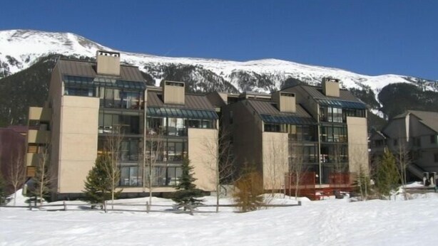 Ein modernes Gebäude mit großen Fenstern und einem schneebedeckten Berg im Hintergrund.