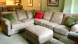 Ein modulares Sofa mit mehreren Kissen, ein passendes Ottomanen und ein Essbereich mit Tisch und Stühlen.