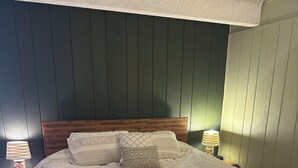 Ein Schlafzimmer mit einem Bettgestell aus Holz, einer gesteppten Bettdecke und zwei Nachttischlampen.