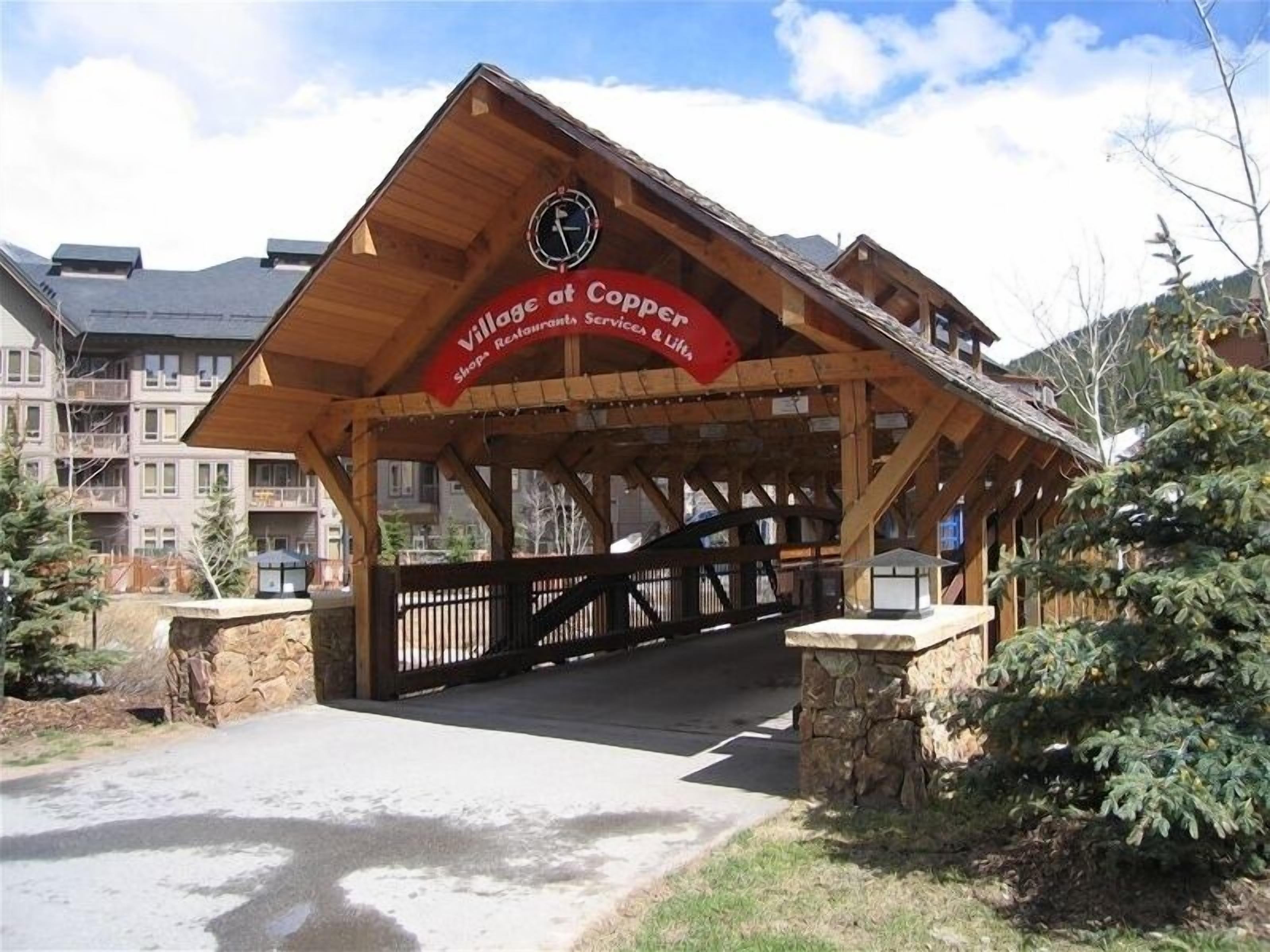 Une entrée couverte en bois mène au Village at Copper, et une enseigne indique l’emplacement des boutiques, des restaurants et des services.