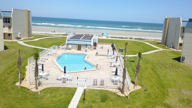A pool area with a view of the beach and ocean.