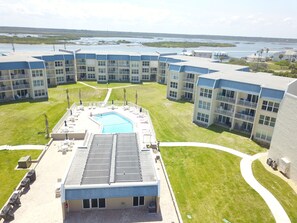 A hotel with a swimming pool, multiple balconies, and a view of the water.