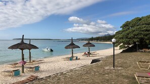 Una spiaggia con ombrelloni, lettini e una barca.