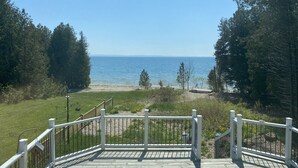A wooden deck with white railings overlooking a beach and ocean. - LaBarbe Bleu on Lake Michigan (Saint Ignace)