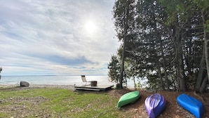 A grassy area with a bench and a wooden platform overlooking a body of water, surrounded by trees. - LaBarbe Bleu on Lake Michigan (Saint Ignace)