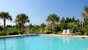 A clear blue pool surrounded by palm trees and lounge chairs.