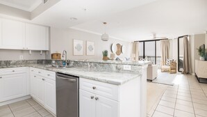 A modern kitchen with white cabinets, a granite countertop, and a built-in dishwasher. - Stay @ Paradise Peak on Folly Beach (Folly Beach)