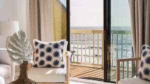 Un balcone con vista sul mare, un divano bianco con cuscini decorati e una pianta ornamentale.
