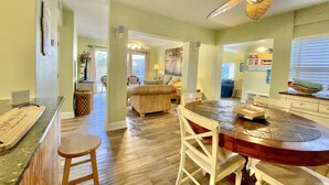 A spacious kitchen with a dining area, wooden flooring, and a ceiling fan.