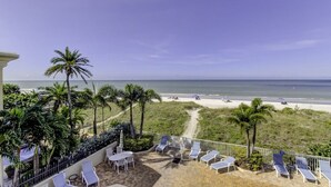 A balcony with lounge chairs and a view of the beach.