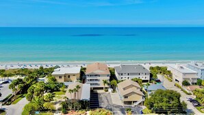 A coastal residential area with beachfront properties, including houses with balconies and a beach in the background.