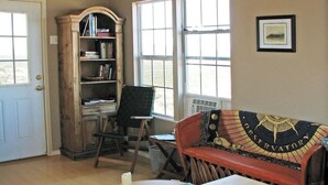 A room with a wooden desk, a bookshelf, a chair, a couch, and a window. - Terlingua Ranch Retreat: Enviro Friendly Home (Terlingua)
