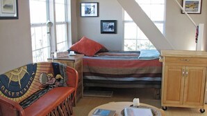 A cozy room with a bed, a wooden cabinet, a small table with a candle, and a couch with a blanket. - Terlingua Ranch Retreat: Enviro Friendly Home (Terlingua)