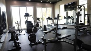 Une salle de sport équipée de tapis de course, d’appareils de musculation et d’haltères.