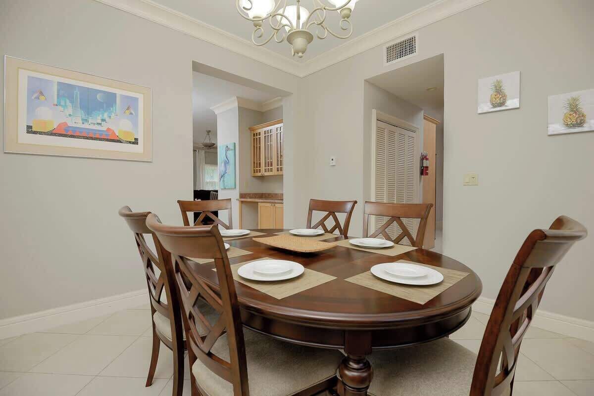 A dining room with a round table, six chairs, and a chandelier.