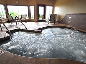 Un área de hidromasaje con piscina, sillas y vistas al exterior.