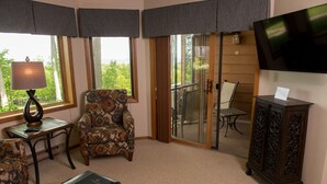 A room with a patterned armchair, a table with a lamp, a cabinet, and a TV on the wall. - Magnificent Water View Condo (Egg Harbor)